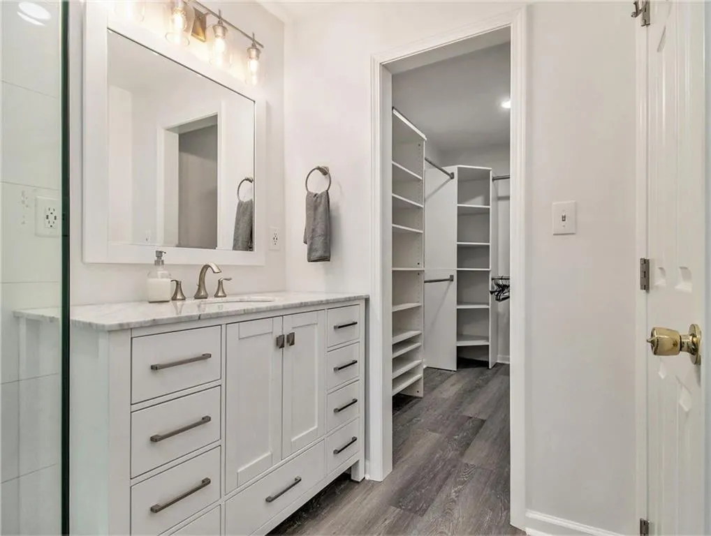 White vanity with a stone countertop, brushed nickel faucet, and undermount sink