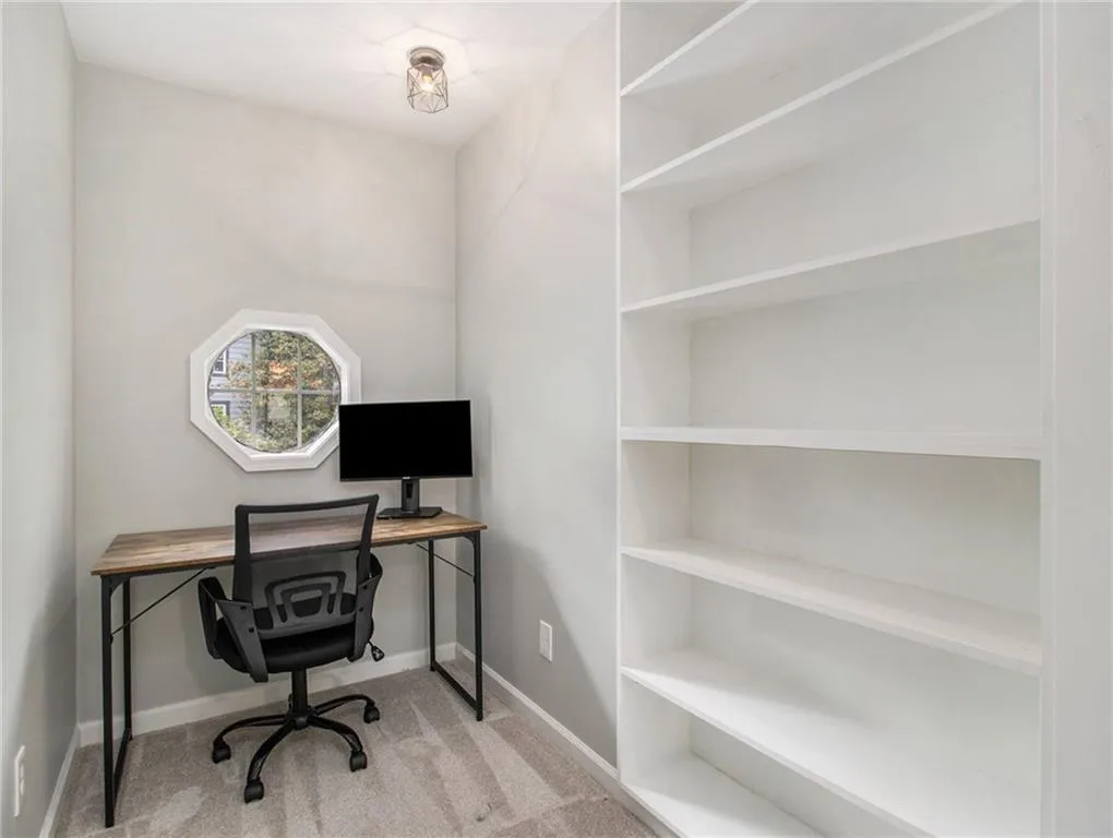 Octagonal window, flush mount ceiling fixture, built-in shelving, and carpeted flooring