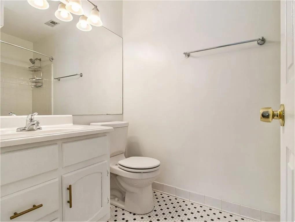 Vanity with white cabinetry, polished chrome faucet, and white countertop