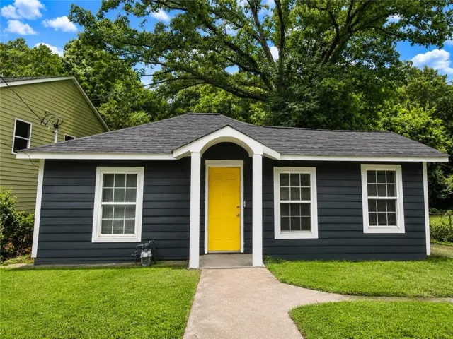 Charcoal gray siding with white trim, a bright yellow front door, and a dark shingle roof