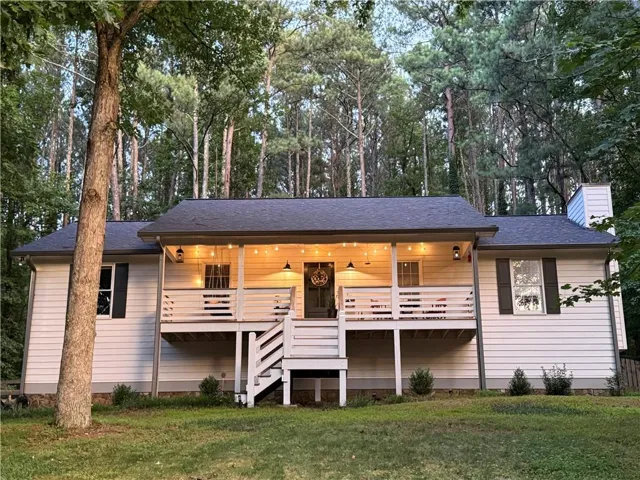 Raised deck with string lighting, white horizontal siding, and dark shutters