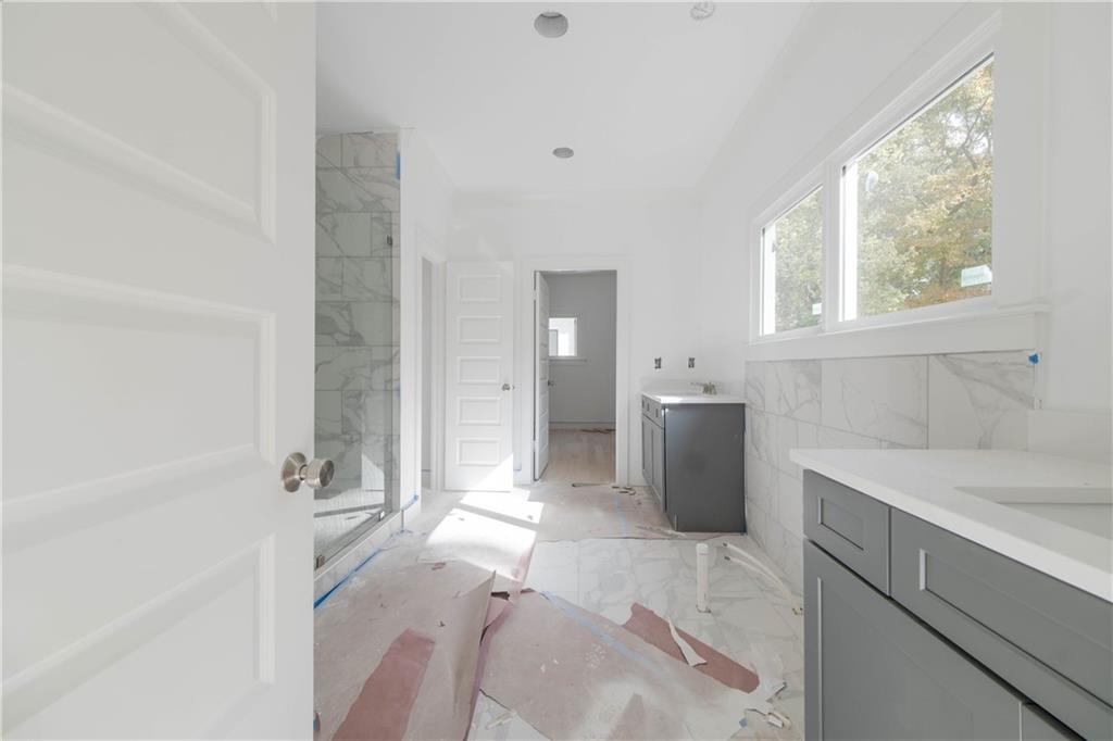 Bathroom featuring tile walls, vanity, and a shower with door