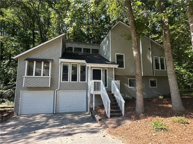 Contemporary exterior with a two-car garage, multiple windows, and a raised entry with white railings