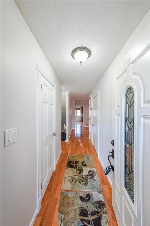 Hallway featuring light hardwood / wood-style floors and a textured ceiling