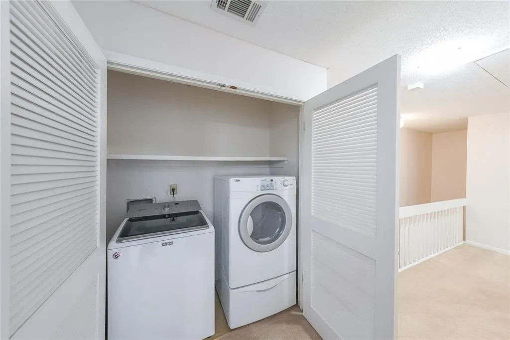 Clothes washing area with light carpet and independent washer and dryer