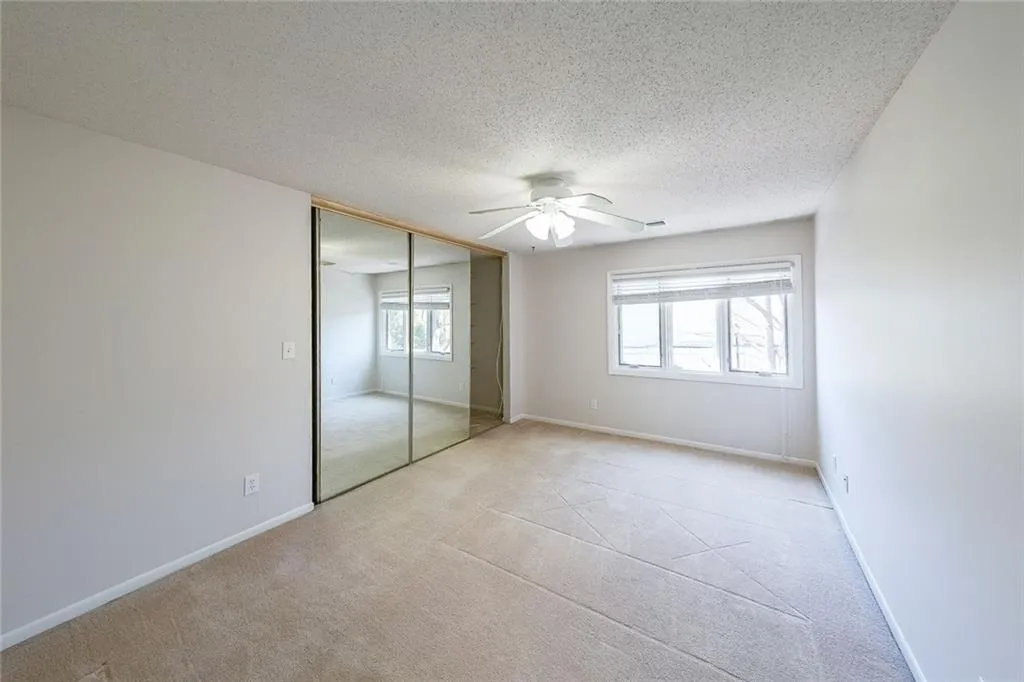 Unfurnished bedroom featuring light colored carpet, a closet, ceiling fan, and a textured ceiling