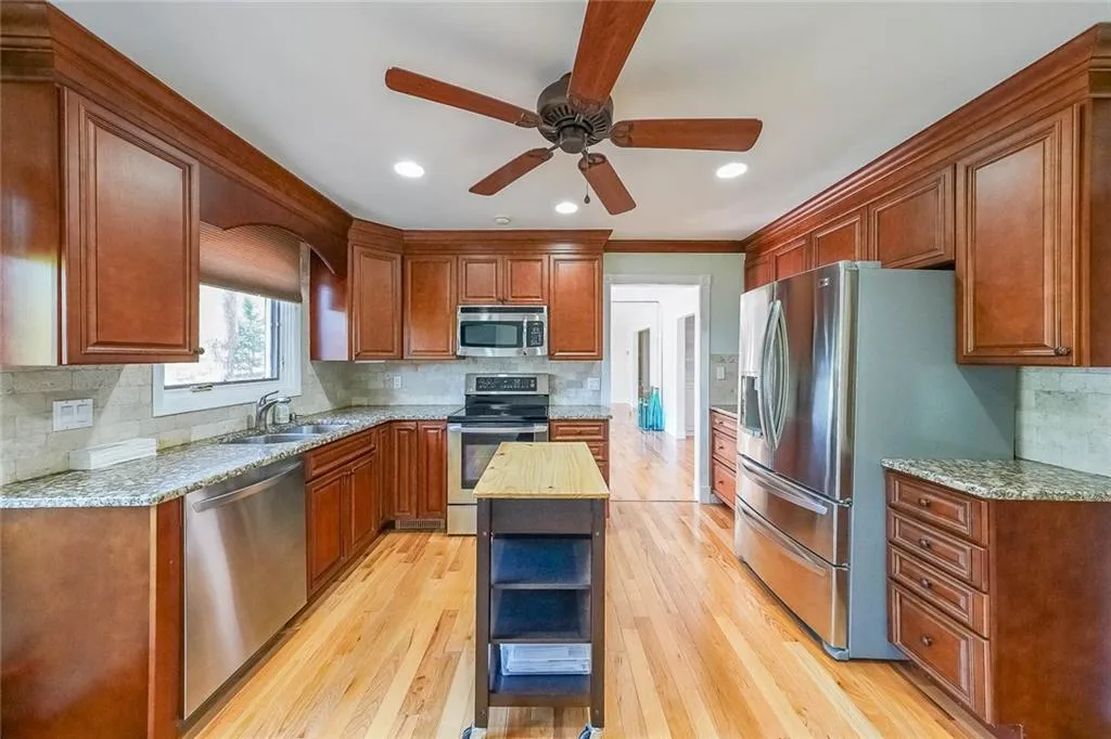 Kitchen featuring a kitchen island, light hardwood / wood-style flooring, ceiling fan, and stainless steel appliances