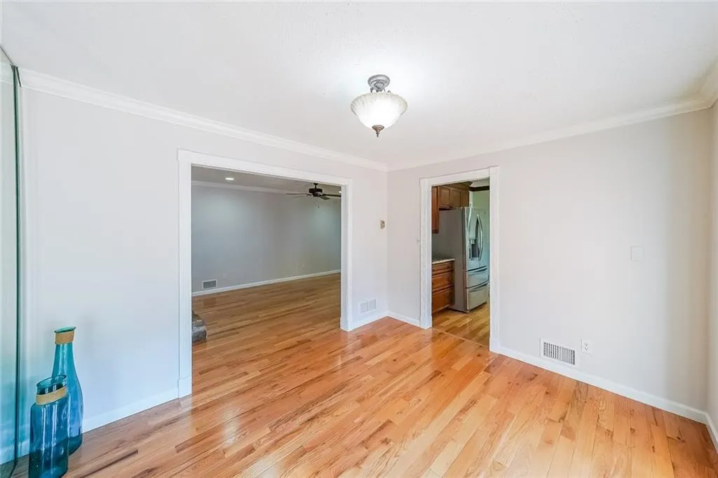 Empty room featuring ceiling fan, crown molding, and light wood-type flooring