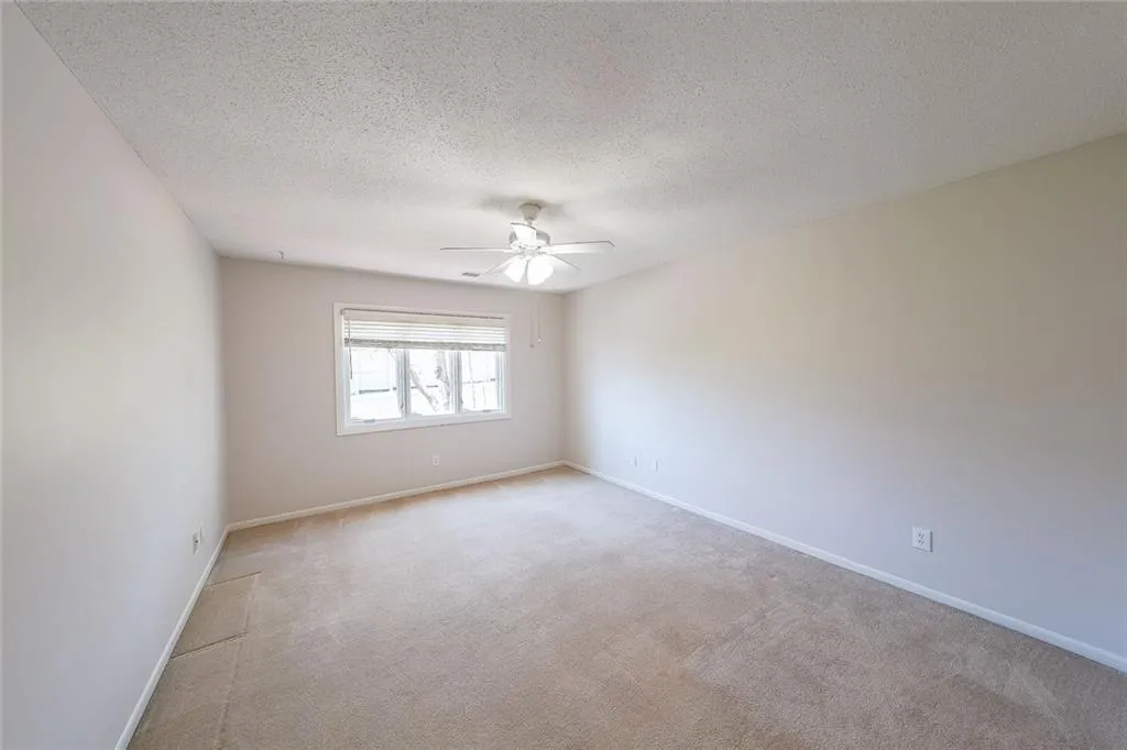 Carpeted spare room with ceiling fan and a textured ceiling