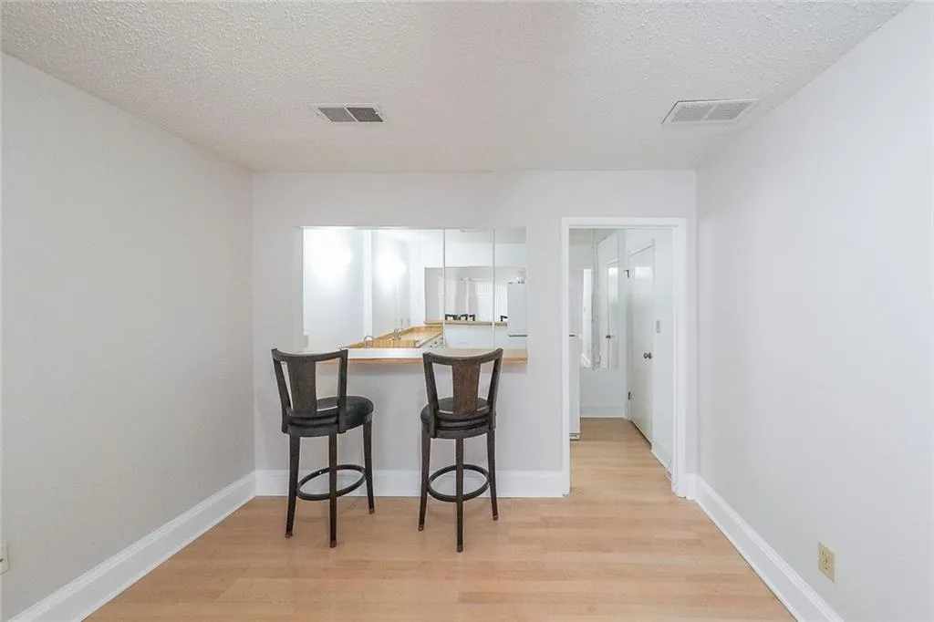Kitchen featuring a textured ceiling, a breakfast bar, light wood-type flooring, and white cabinetry