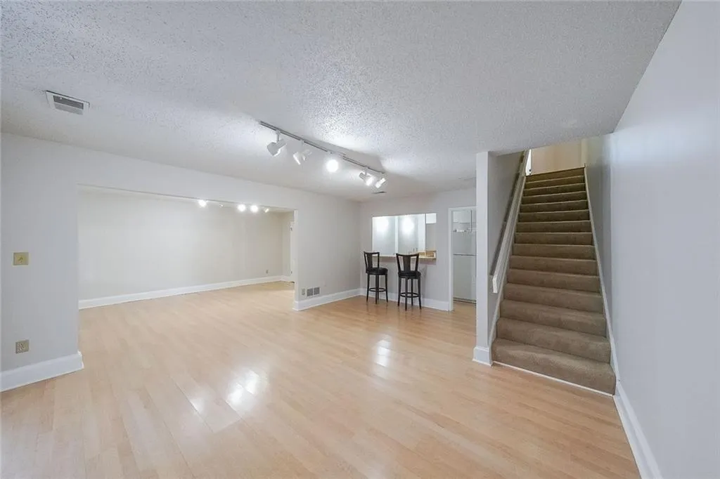 Basement featuring a textured ceiling, light hardwood / wood-style flooring, and rail lighting