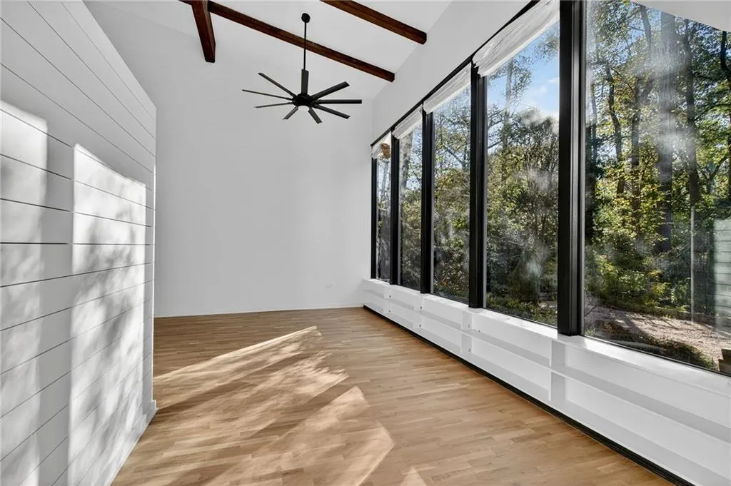 Unfurnished sunroom with beamed ceiling, wood finished floors, and high vaulted ceiling