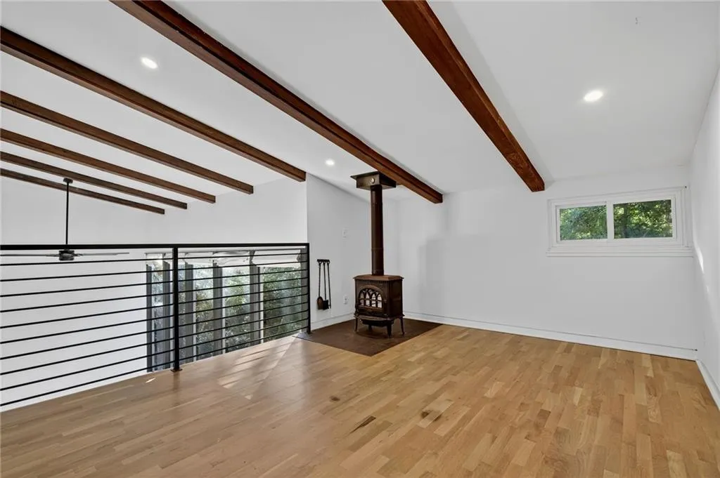 Unfurnished living room featuring a wood stove, recessed lighting, light wood-type flooring, and beam ceiling