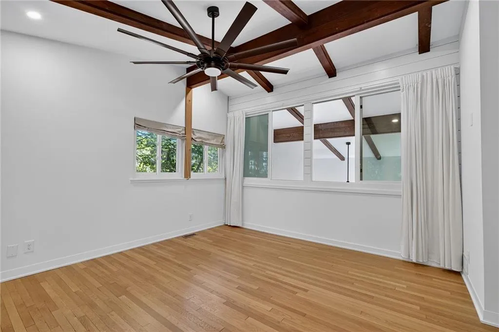 Unfurnished room with beam ceiling, light wood-style floors, and ceiling fan