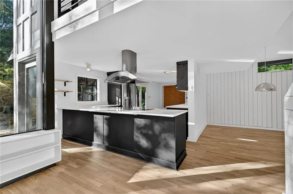 Kitchen featuring light wood-style floors, island exhaust hood, pendant lighting, a peninsula, and wooden walls