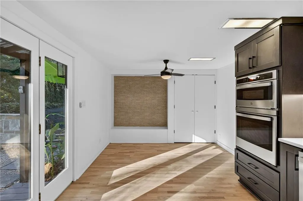 Kitchen featuring light wood-style flooring, double oven, dark brown cabinets, light countertops, and ceiling fan