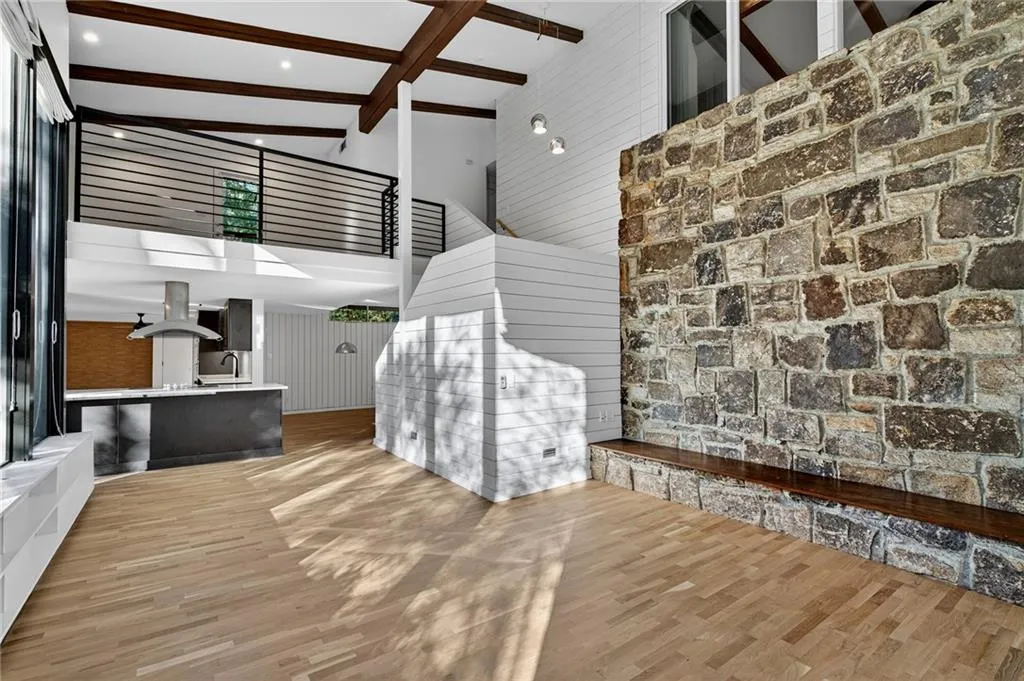 Unfurnished living room featuring beam ceiling, high vaulted ceiling, wood finished floors, and wood walls