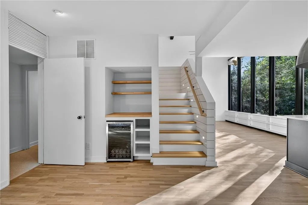Bar area with open shelves, beverage cooler, light wood-type flooring, and stairs