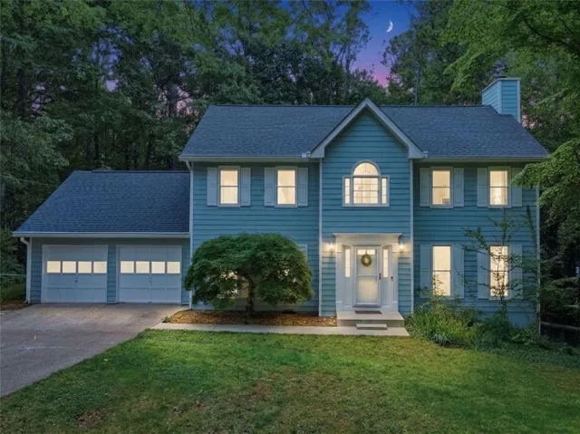 Two-story residence featuring light blue siding, a two-car garage, and a gabled roof
