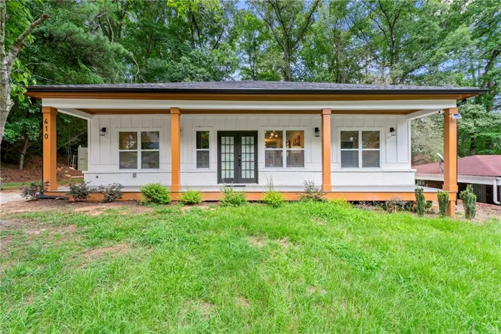 White exterior siding with dark trim, featuring a covered front porch with natural wood columns