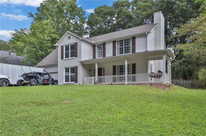 Gable roofline, white siding exterior, covered front porch, white porch railing, and a prominent chimney