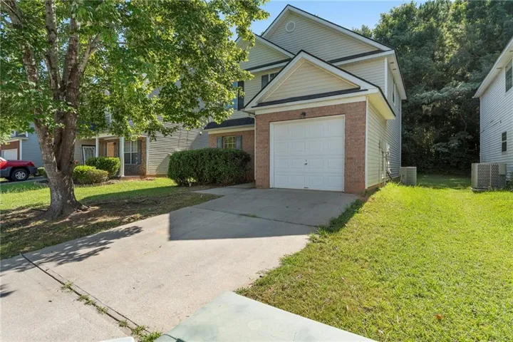 View of front of house with driveway, brick siding, a front lawn, and a garage