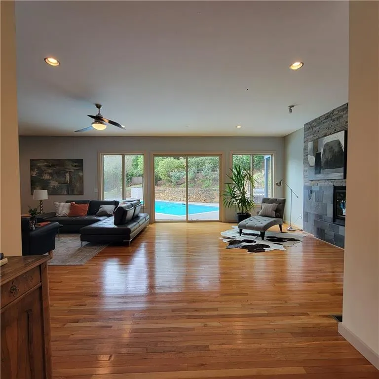 Living area with light wood-style floors, healthy amount of natural light, recessed lighting, a fireplace, and a ceiling fan