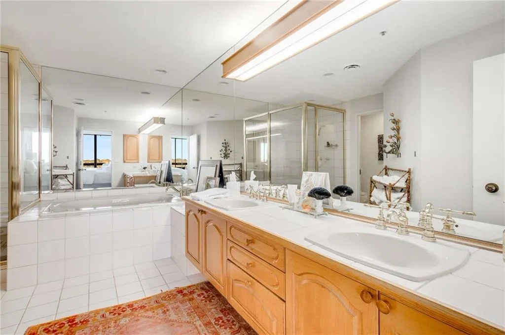 Full bath with double vanity, a shower stall, a garden tub, and light tile patterned floors