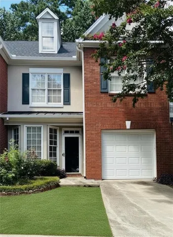 Brick and stucco exterior with a dormer window, an attached single-car garage, and a concrete driveway