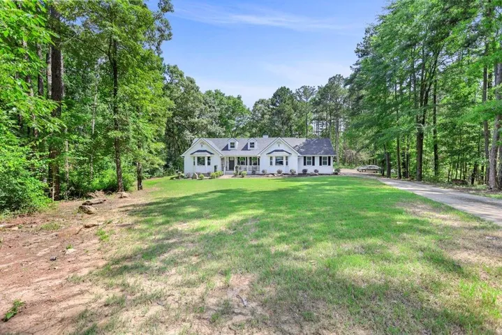 Single-story residence featuring a white exterior, dark shutters, and a covered front porch