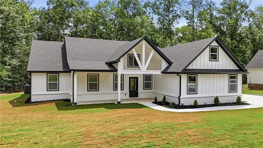 Modern farmhouse style exterior featuring white board and batten siding, dark framed windows, a covered front porch, and a dark shingle roof