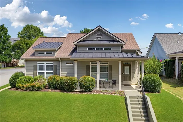 Exterior featuring a covered porch, gabled roof, dormer windows, and a metal awning