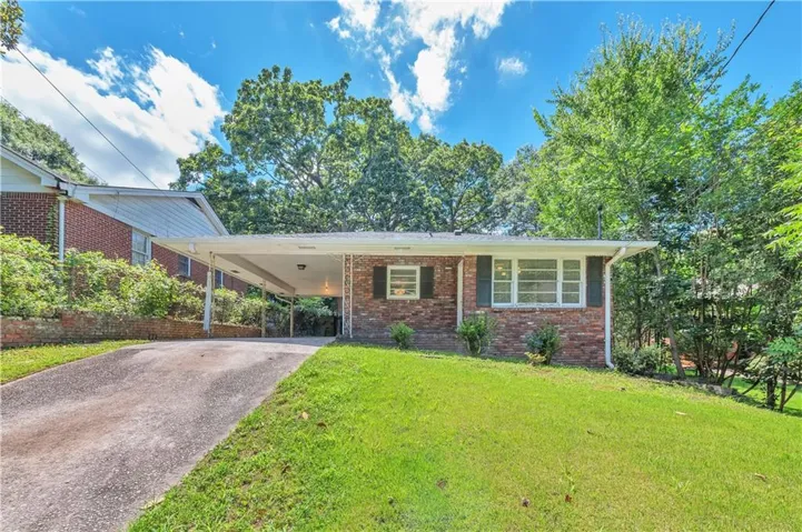 Brick exterior residence featuring a front lawn and a paved driveway
