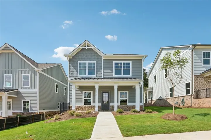 Two-story residence featuring a covered front porch, stone detailing, and a gabled roofline with decorative trim