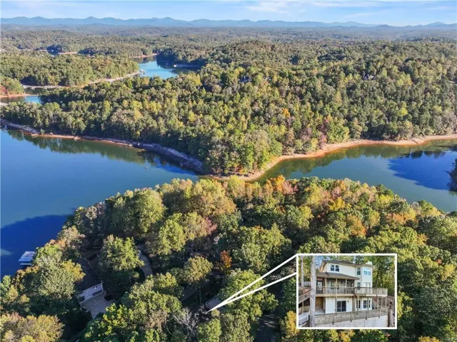 Wooded waterfront property featuring multiple decks, a private dock, and a multi-story residence