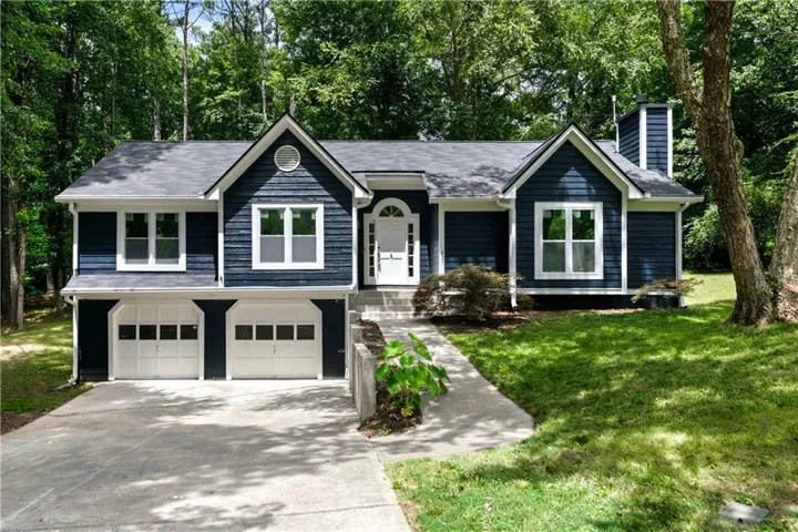 Dark blue siding exterior featuring white trim windows and a prominent white arched entry door