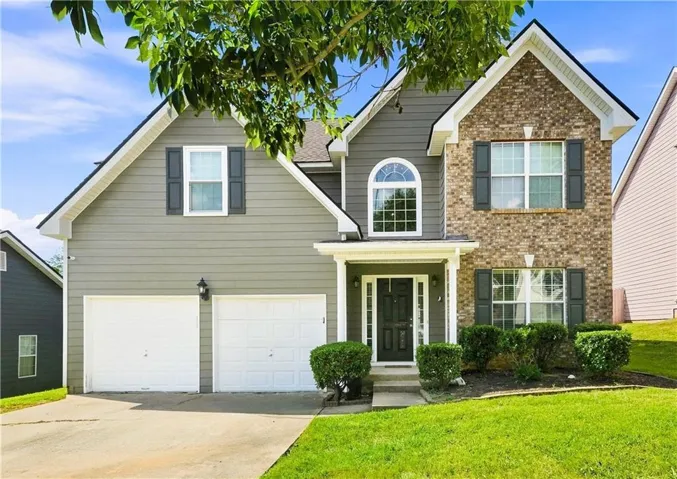 Two-story residence featuring a brick facade with siding accents, an arched window, a covered front entry, and a two-car garage