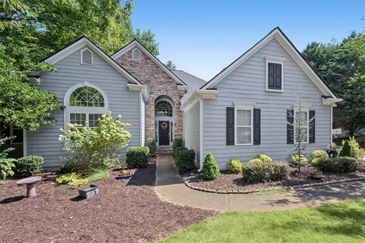 Light blue siding exterior with stone accents, featuring an arched transom window and dark shutters