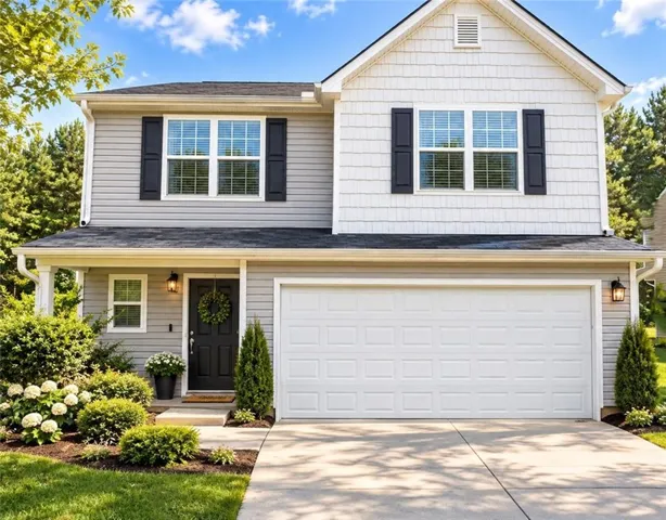 Two-story residence featuring a two-car garage, gray siding, and a covered front porch