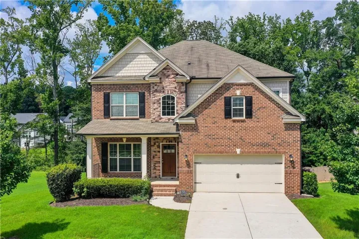 Two-story brick facade residence featuring a covered front porch, an arched entry window, and a two-car garage