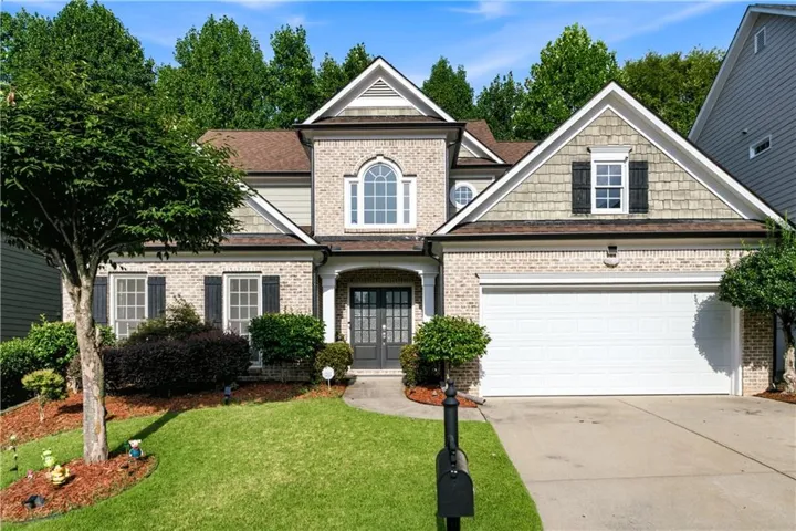 Brick facade with gabled roofline, arched window, and attached two-car garage