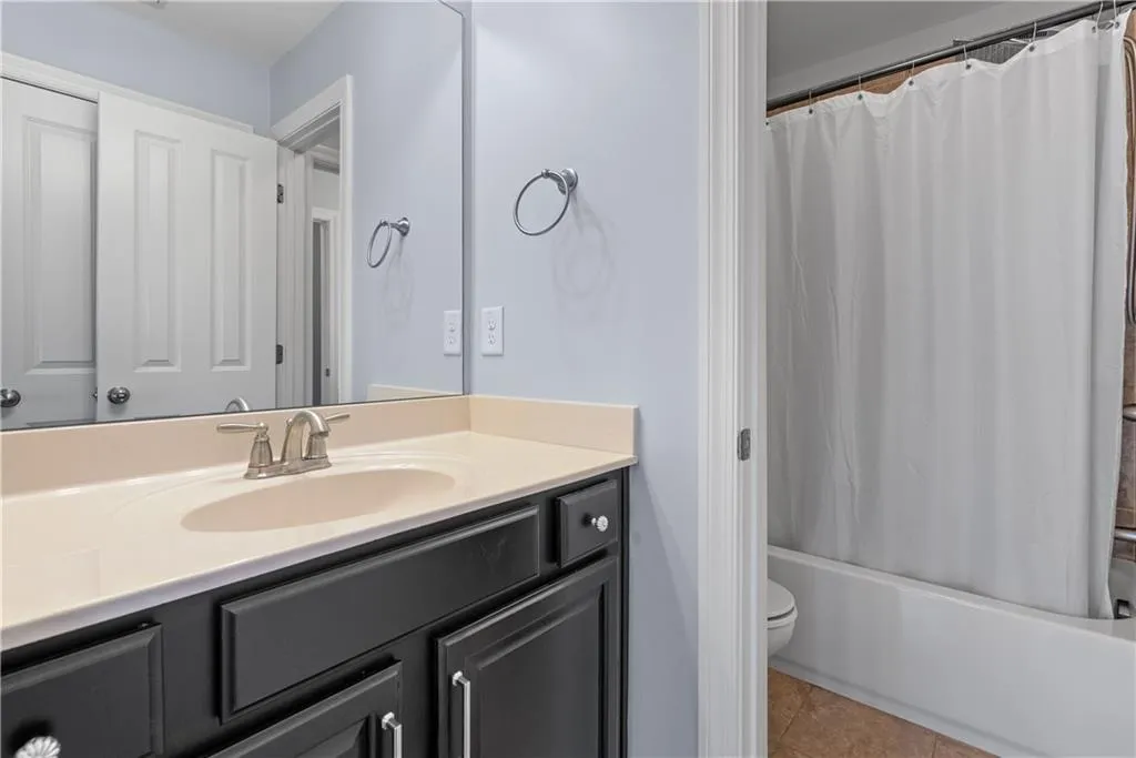 Bathroom with vanity, tile patterned floors, toilet, and shower / tub combo with curtain