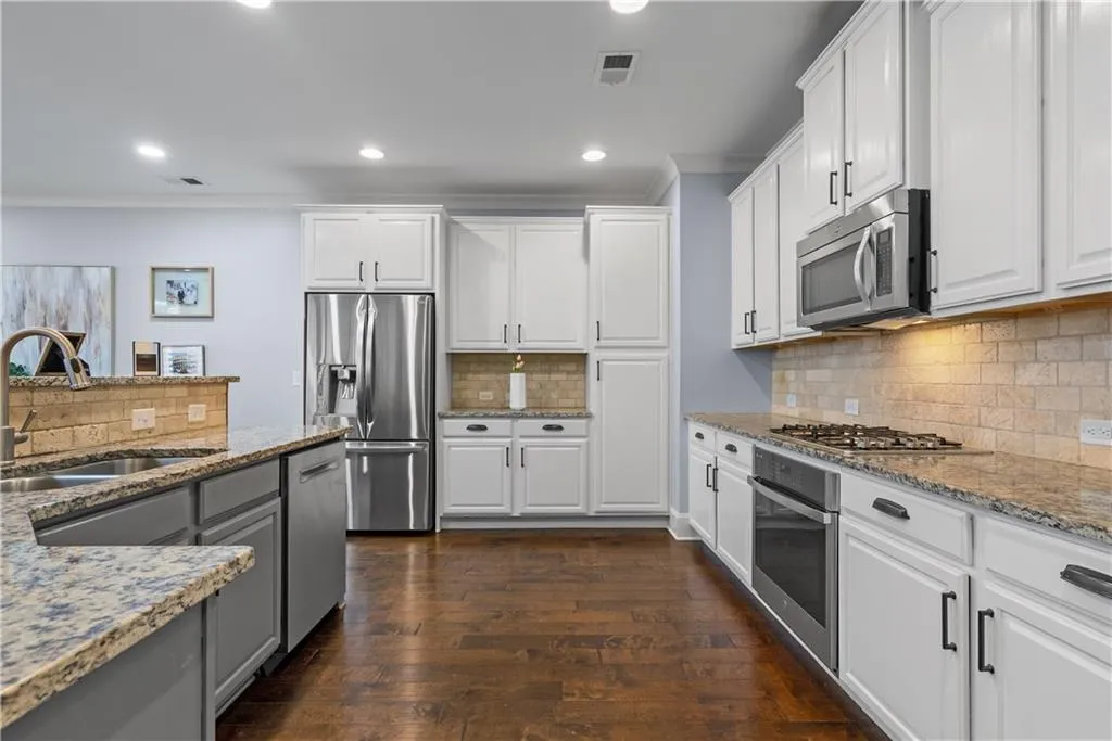 Kitchen features stainless steel appliances, white cabinet and granite countertop