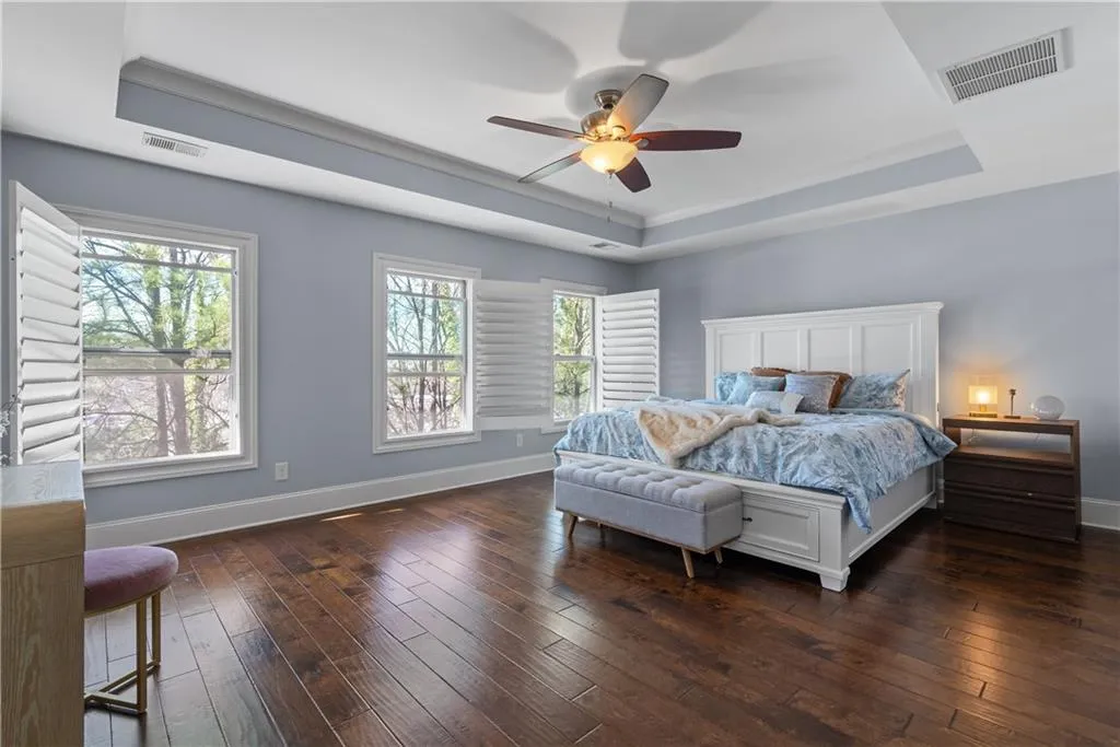 Bedroom featuring visible vents, a raised ceiling, and dark wood-type flooring