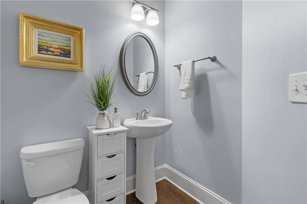 Half bathroom featuring a sink, baseboards, toilet, and wood finished floors