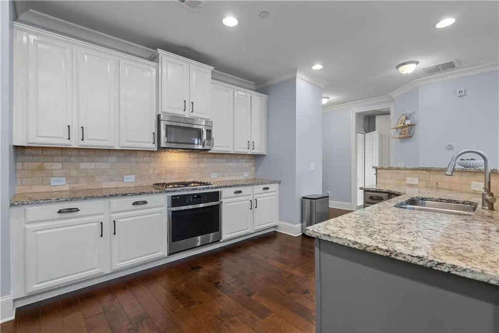 Kitchen with visible vents, a sink, dark wood-style floors, appliances with stainless steel finishes, and crown molding