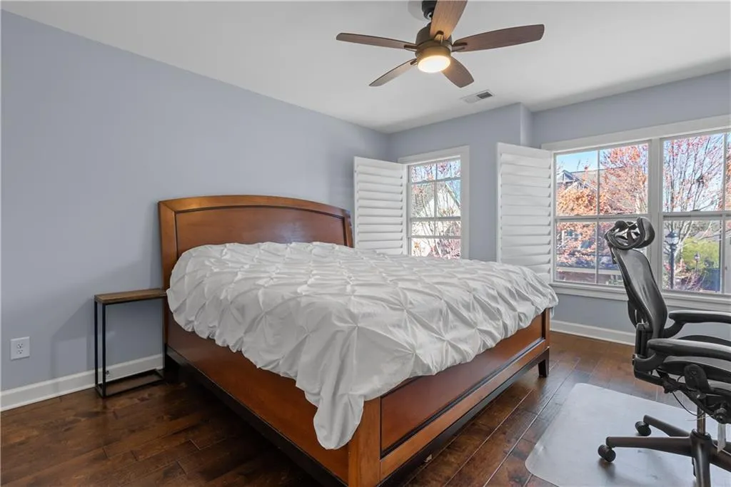 Bedroom with baseboards, visible vents, wood-type flooring, and ceiling fan