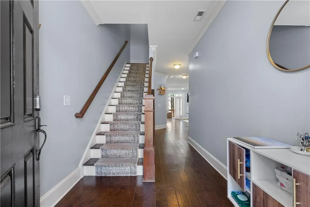 Foyer entrance featuring baseboards, stairs, dark wood-type flooring, and crown molding