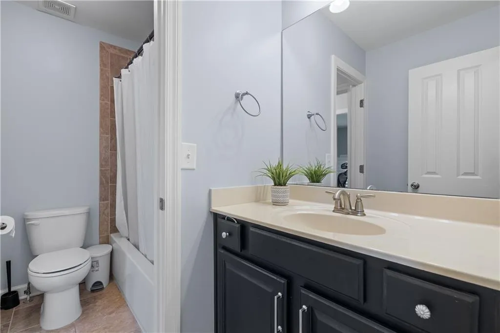Bathroom featuring visible vents, toilet, tile patterned floors, shower / bath combination with curtain, and vanity