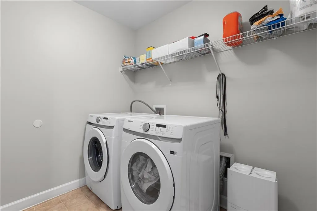 Laundry room with laundry area, light tile patterned floors, baseboards, and independent washer and dryer